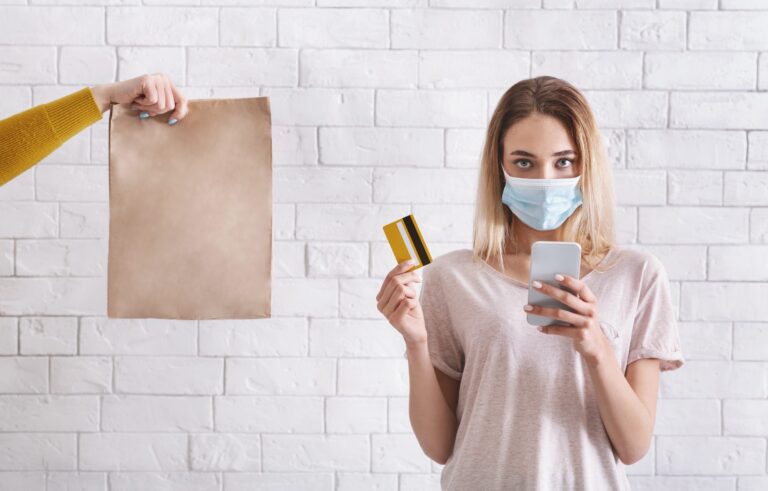 female in protective mask holding credit card and mobile phone Genesis blog.